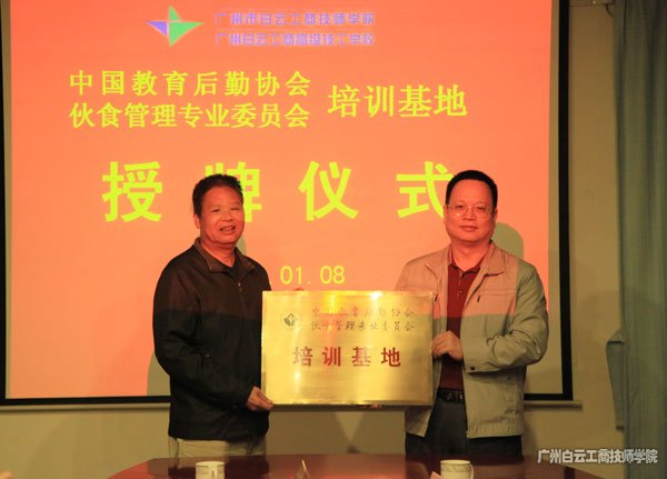 中国教育后勤协会伙食管理专业委员会副主任王淼光（左）向李孟强院长（右）授牌